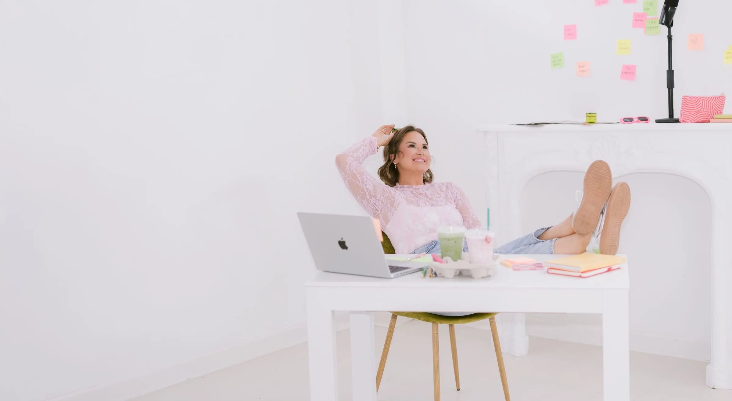 Candace Donnelly at her desk with her feet up, a wall of sticky notes behind her